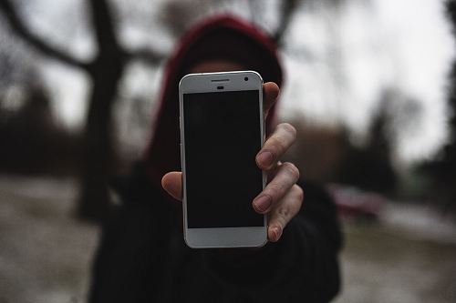 tilt-shift lens photography of person holding smartphone close to camera